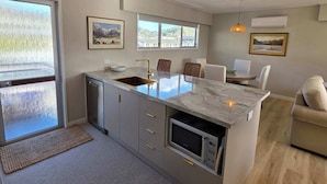 A modern kitchen with a marble countertop, built-in microwave, and a sink. - Comfy Haven in the Heart of Picton (Picton)