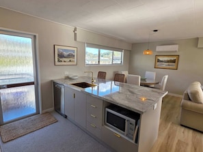 A modern kitchen with a marble countertop, built-in microwave, and a sink.