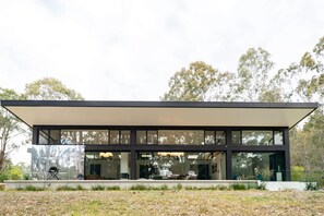 Un edificio moderno con techo plano, amplias ventanas y una zona exterior cubierta.