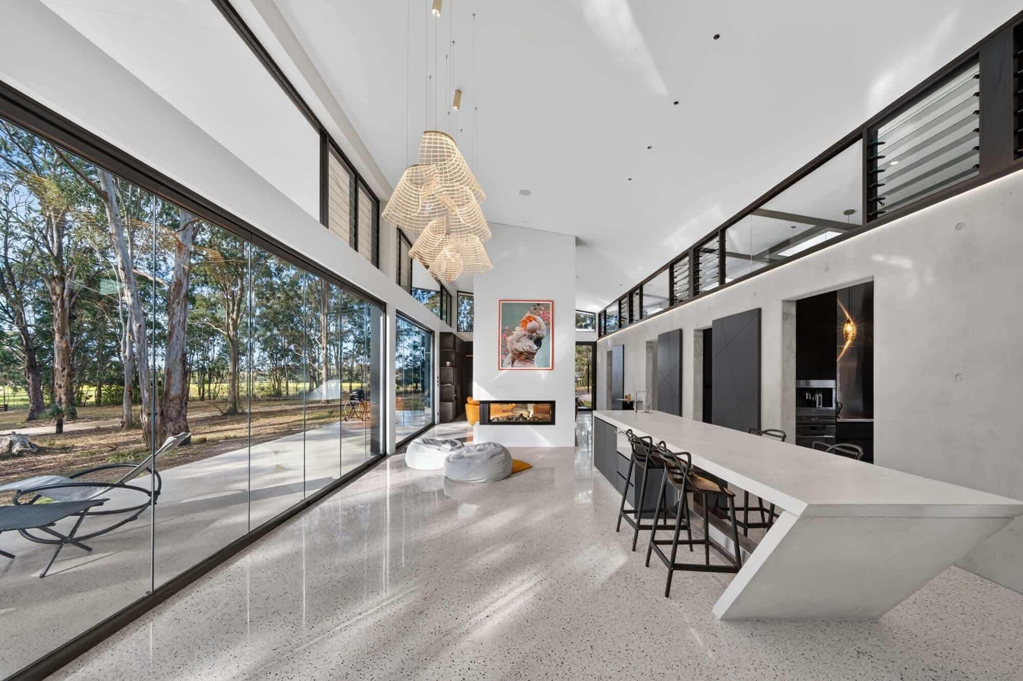 Un intérieur moderne avec de grandes fenêtres, un espace salon central et une cuisine.