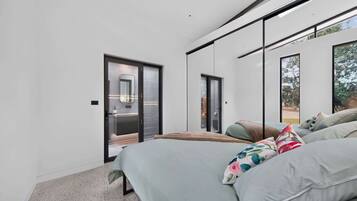 Een moderne slaapkamer met een bed, een groot raam en een schuifdeur naar een badkamer.