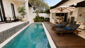 A swimming pool with lounge chairs and a table, surrounded by potted plants and a wooden deck. - Roberto Villas, A Short Scooter Drive to The PadangPadang and Bingn Beach (Pecatu)