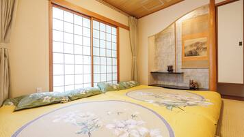 A traditional Japanese-style room with tatami flooring, a shoji screen, and a bed with floral bedding.