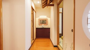 Un pasillo con piso de madera, un cuadro en la pared y una puerta de diseño tradicional.