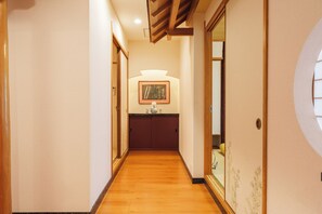 A hallway with wooden flooring, a framed picture on the wall, and a door with a traditional design.