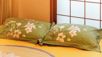A bed with green floral bedding and a window with a grid pattern.