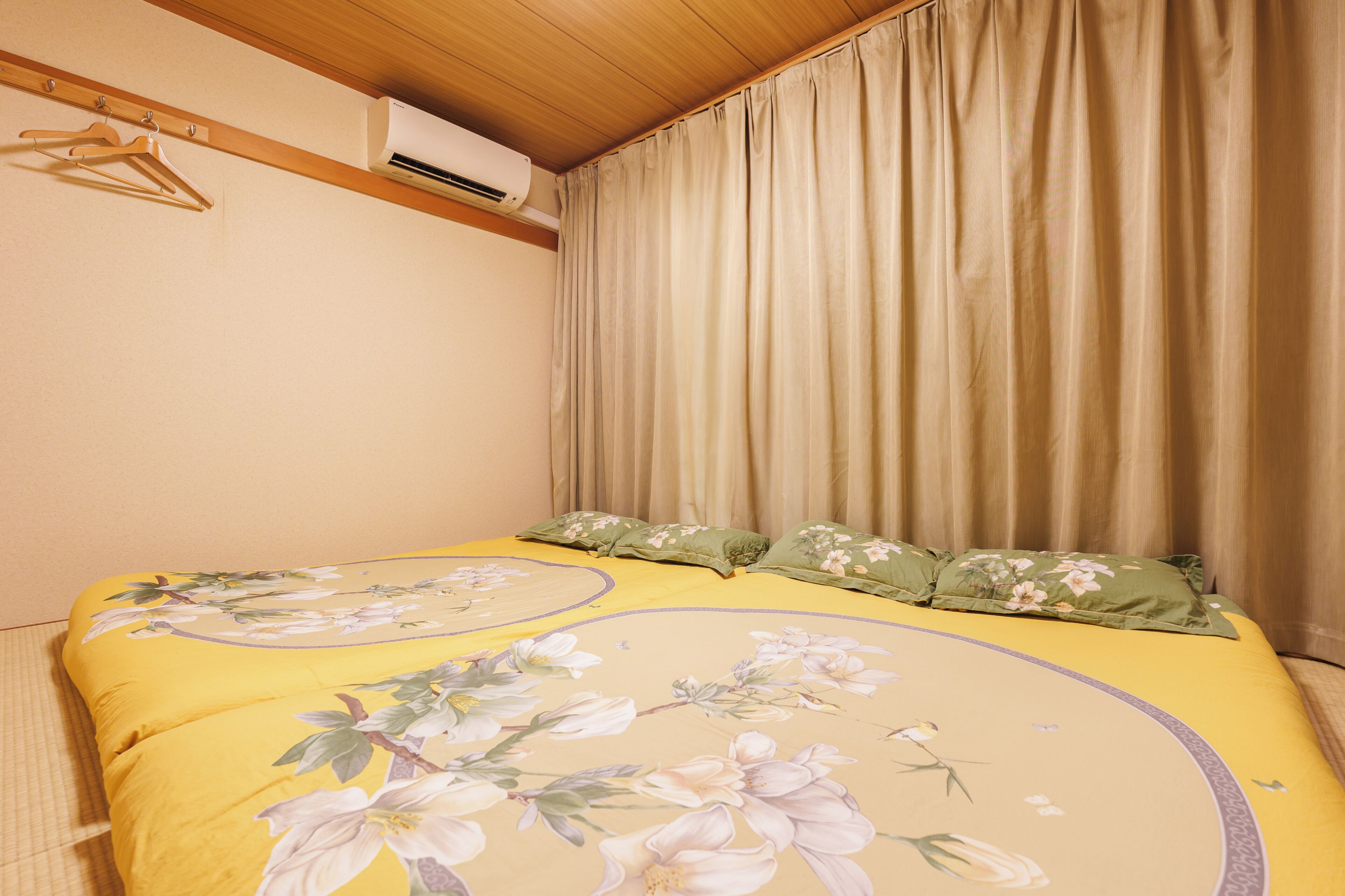 A bedroom with a bed, a hanging clothes rack, and an air conditioning unit.