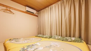 Un dormitorio con una cama, un perchero y un equipo de aire acondicionado.