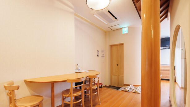 Una habitación con una mesa y sillas de madera, una puerta y un suelo de baldosas.