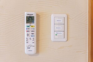 A wall-mounted thermostat and control panel with Japanese labels, indicating temperature settings and room functions.