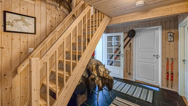 A wooden staircase with a handrail, a white door with a keyhole, and a framed picture on the wall. - Nice home in Skare with house a mountain view (Skare)
