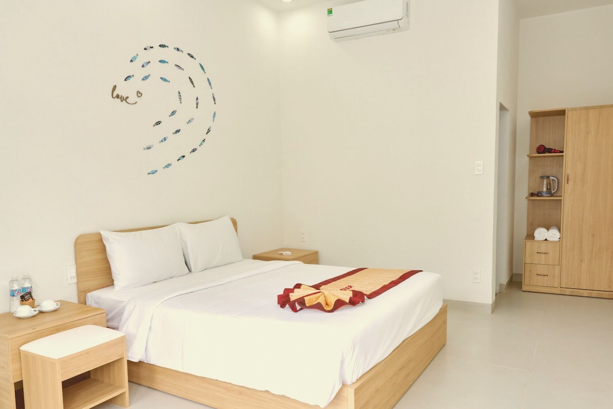 A hotel room with a bed, bedside table, and a wardrobe.