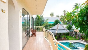 A balcony with a view of a swimming pool, surrounded by tropical vegetation. - Gem's House (Mui Ne)