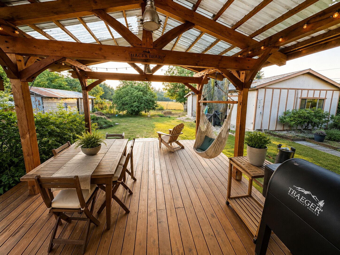 A wooden deck with a table and chairs, a hanging chair, and a grill.
