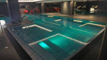 Piscina com várias pistas e área de bar com cadeiras vermelhas.