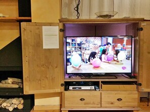Un televisor fixat a un moble de fusta amb una prestatgeria a sota.