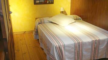 A room with a bed, a nightstand, a lamp, and a wall-mounted picture.