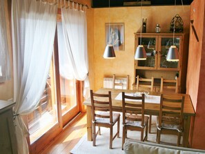 A dining area with a wooden table and chairs, a cabinet with glass doors, and a window with curtains. - Perfect retreat with privileged views of Masella (Puigcerdà)