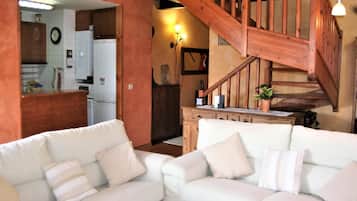 Ein Wohnzimmer mit weißen Sofas und einer Holztreppe.