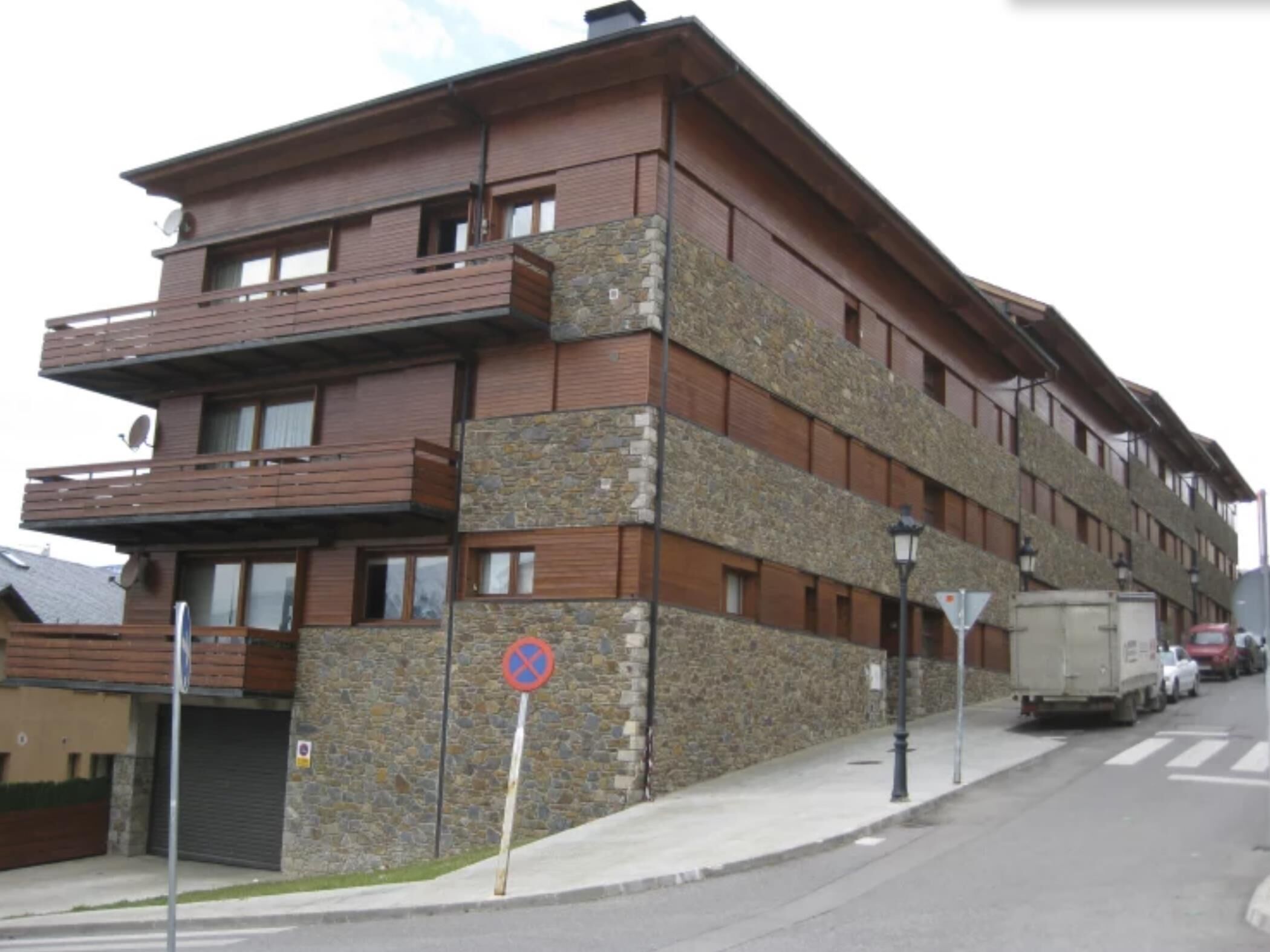 A multi-story building with balconies and a no parking sign.