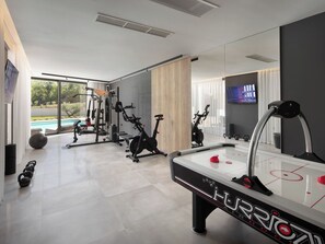 A modern home gym with exercise equipment, a pool, and a TV. - Villa H2 by Interhome (Labin)