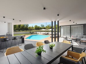 Een modern terras buiten met een zwembad, bar en zitplaatsen.