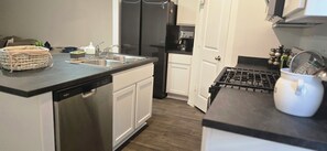 A modern kitchen with a dishwasher, double sink, and a coffee machine. - Family-Friendly New Townhome in lovely Wayside community (Uhland)