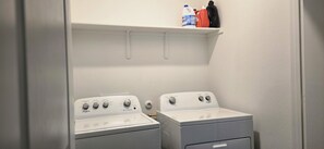A laundry area with two Whirlpool dryers and a shelf above containing cleaning supplies. - Family-Friendly New Townhome in lovely Wayside community (Uhland)