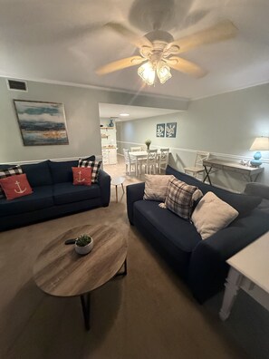 A living room with two sofas, a coffee table, and a dining area with a table and chairs. - Daytona Riverfront Haven Retreat on the Halifax (Port Orange)