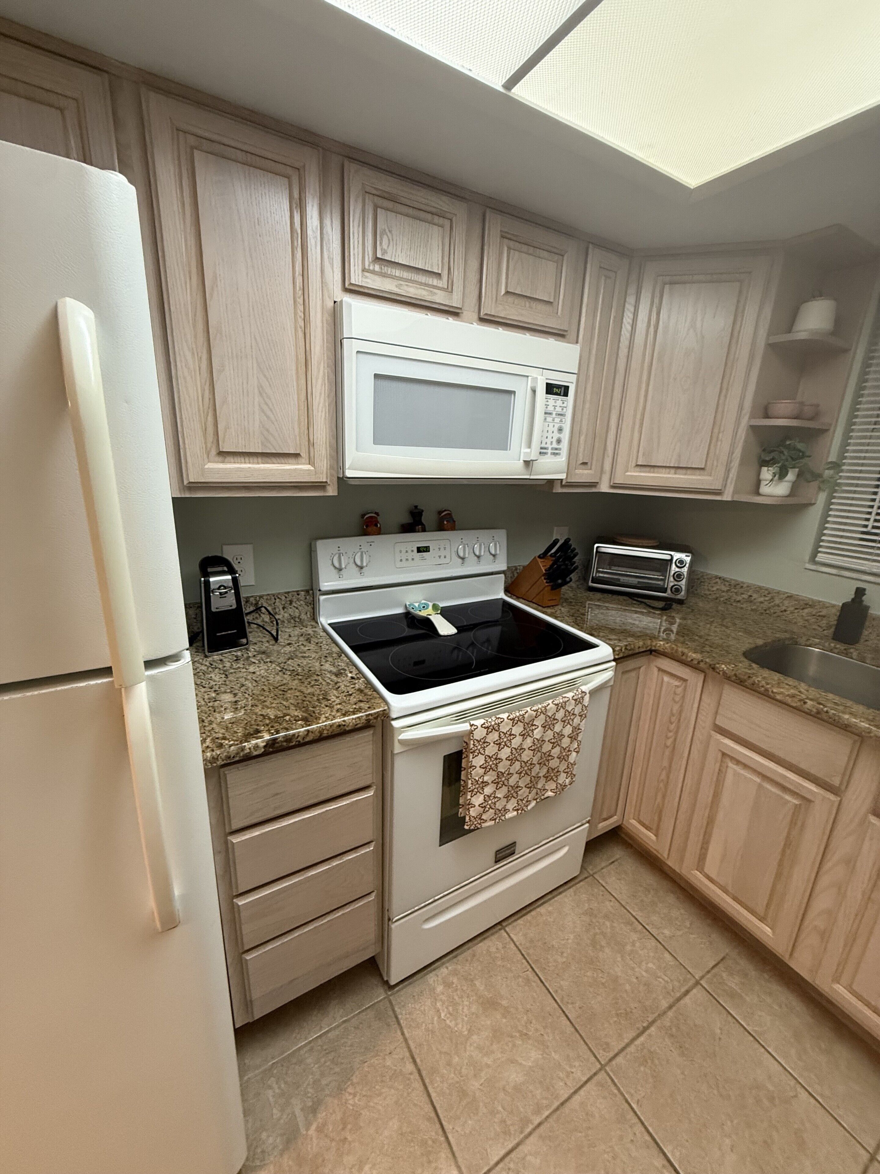Una cocina equipada con refrigerador, microondas, estufa, horno y tostadora.