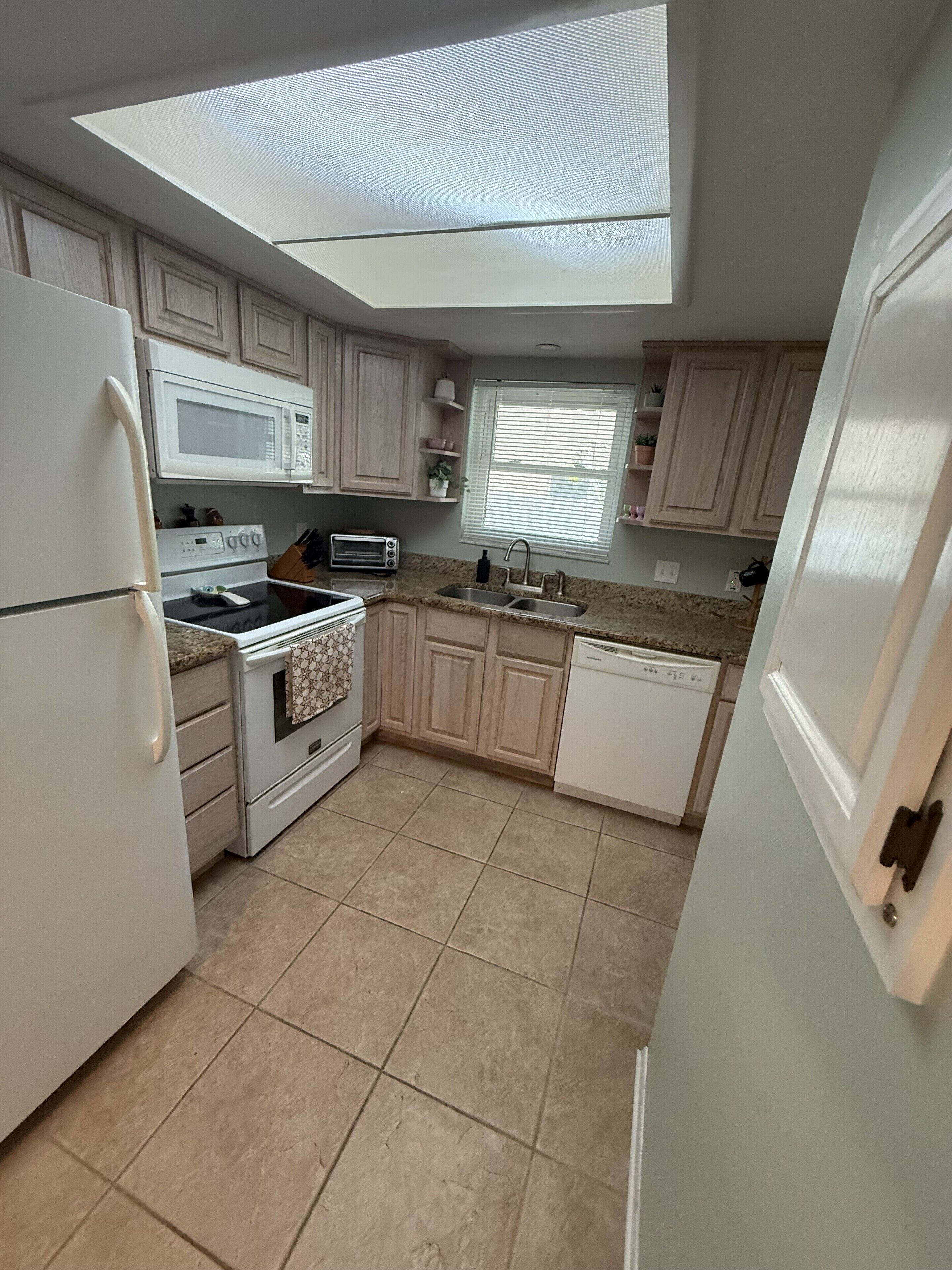 A compact kitchen with a microwave, oven, toaster, sink, and dishwasher.