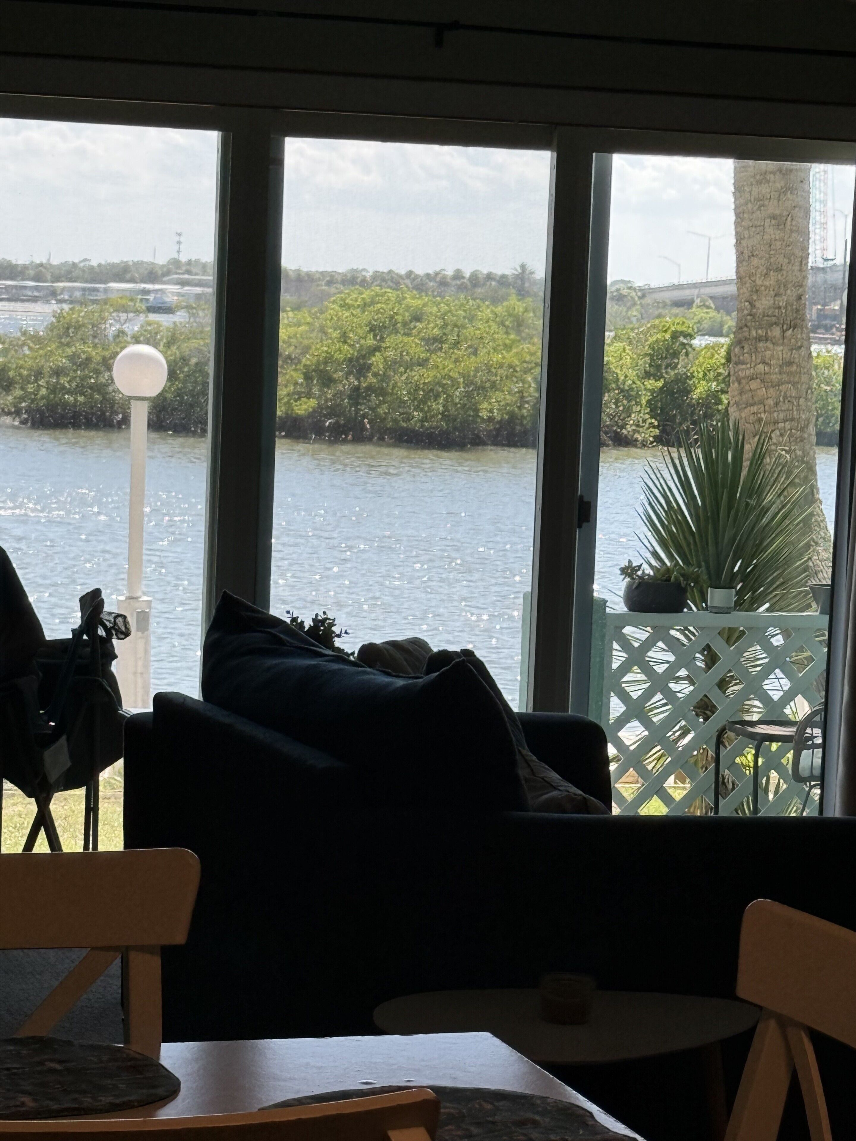 A room with a view of a body of water, a sofa, a chair, and a small table.