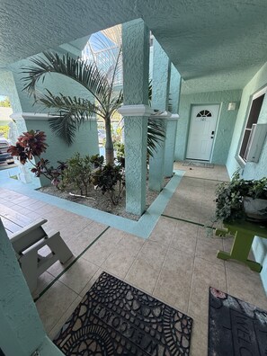A covered outdoor area with a palm tree, a bench, and a door marked with the number 101. - Daytona Riverfront Haven Retreat on the Halifax (Port Orange)