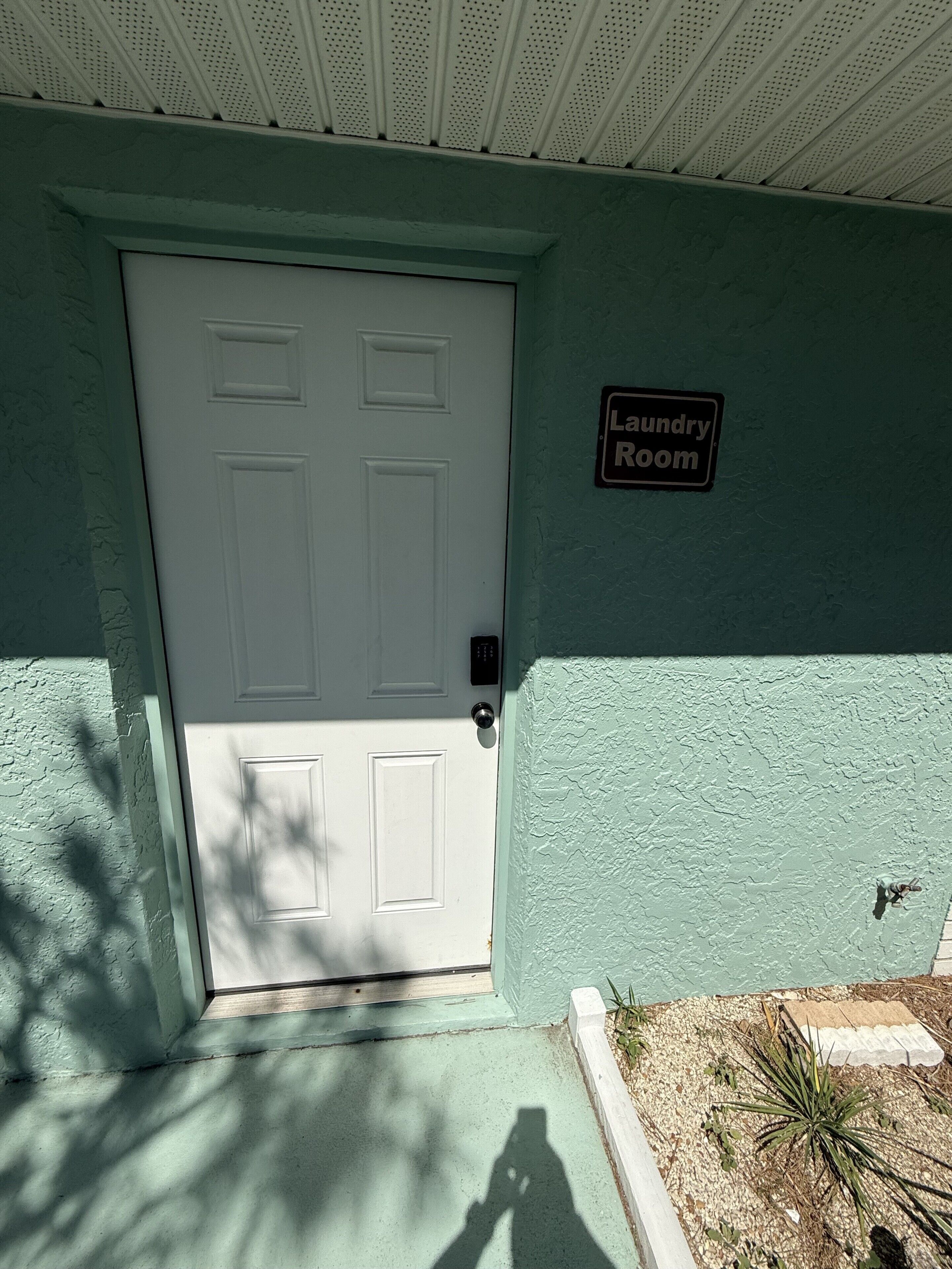 Una puerta blanca con un letrero que dice 'Laundry Room' sobre ella, frente a una pared verde azulado.