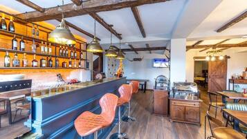 A bar area with a wooden ceiling, bar stools, and a variety of bottles on shelves.