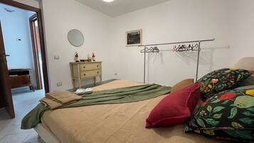 Une chambre à coucher avec un lit, une commode, un miroir et un portant à vêtements.