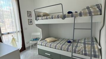 Una stanza con un letto a castello, una scrivania, una sedia e una finestra con tende.