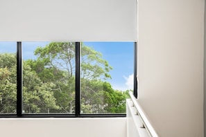 Una habitación con un ventanal que ofrece vistas a árboles y al cielo.