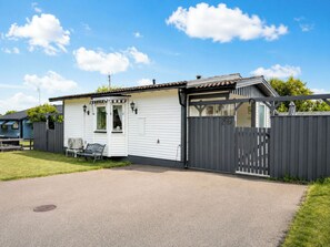 Ein eingeschossiges Gebäude mit weißer Fassade und grauer Umzäunung.