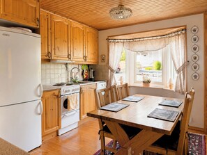 Eine Küche mit Holzschränken, einem weißen Kühlschrank, einem Herd und einem Esstisch mit Stühlen.