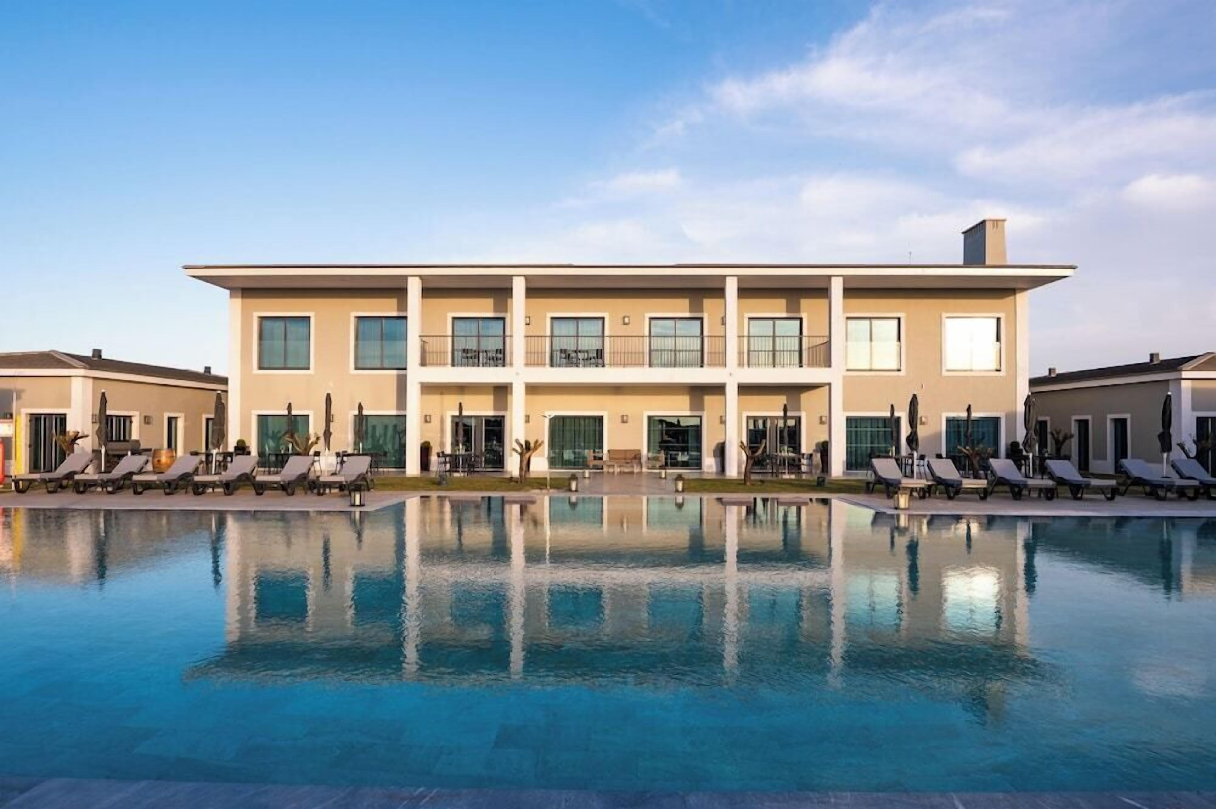 A modern hotel with a large pool and multiple lounge areas.