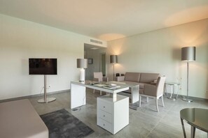 A modern living room with a glass-top coffee table, a sofa, a TV, and two floor lamps. - Vila Gale Collection Monte do Vilar (Beja)