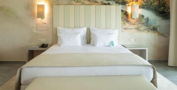 Habitación de hotel con una cama grande, dos mesitas de noche, una lámpara de pared y un cuadro.