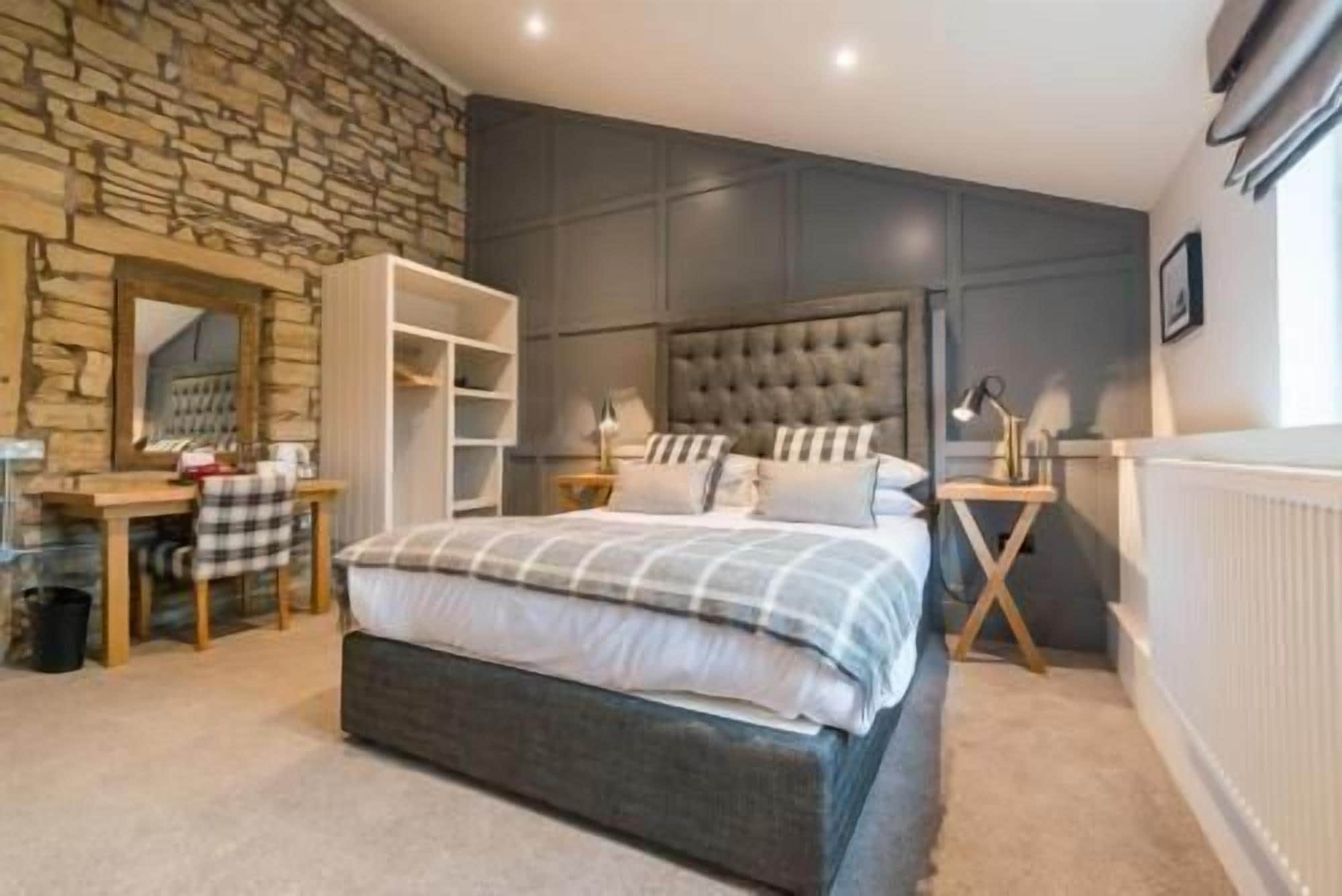 A bedroom with a bed, a desk, and a wardrobe.