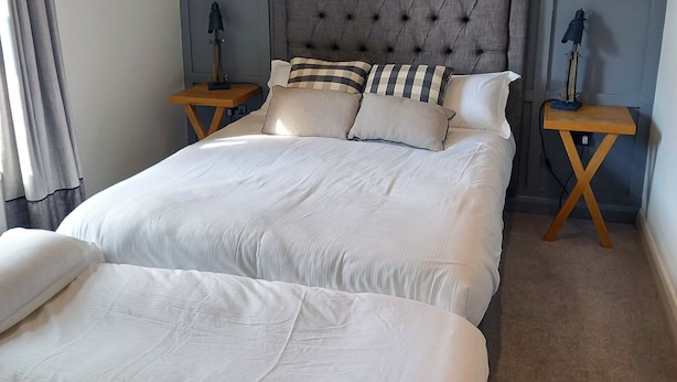 Ein Doppelbett mit gebogenem, gepolstertem Kopfteil, zwei Nachttische und eine passende Bank.