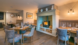 A restaurant with a fireplace, wooden tables, and cushioned chairs. - The Forest (Burnley)