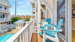 Ein Balkon mit Pool, eine kleine Gartenhütte und Blick auf benachbarte Gebäude.