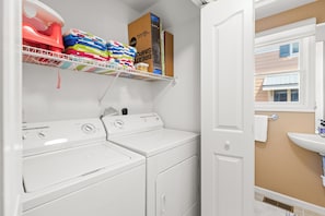 A laundry room with two front-loading washers and dryers, a shelf with folded towels, and a box labeled 'SIMPLY BRIGHT.' - Oceanside,Pool,Skee-ball,Nintendo,Pets,Arcades (Ocean City)