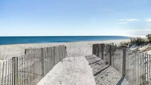 Ein Strandweg, der zum Meer führt, gesäumt von Holzzaunen.