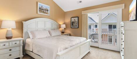 A bedroom with a bed, nightstands, a ceiling fan, and a view of a balcony.